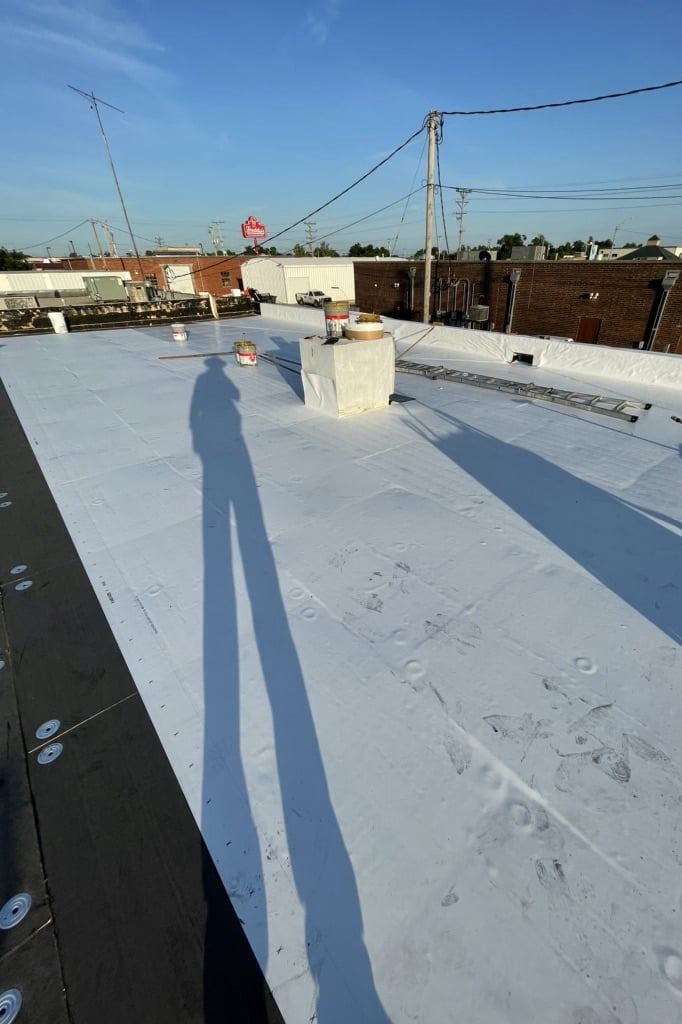 A shadow of a person is cast on a white roof.