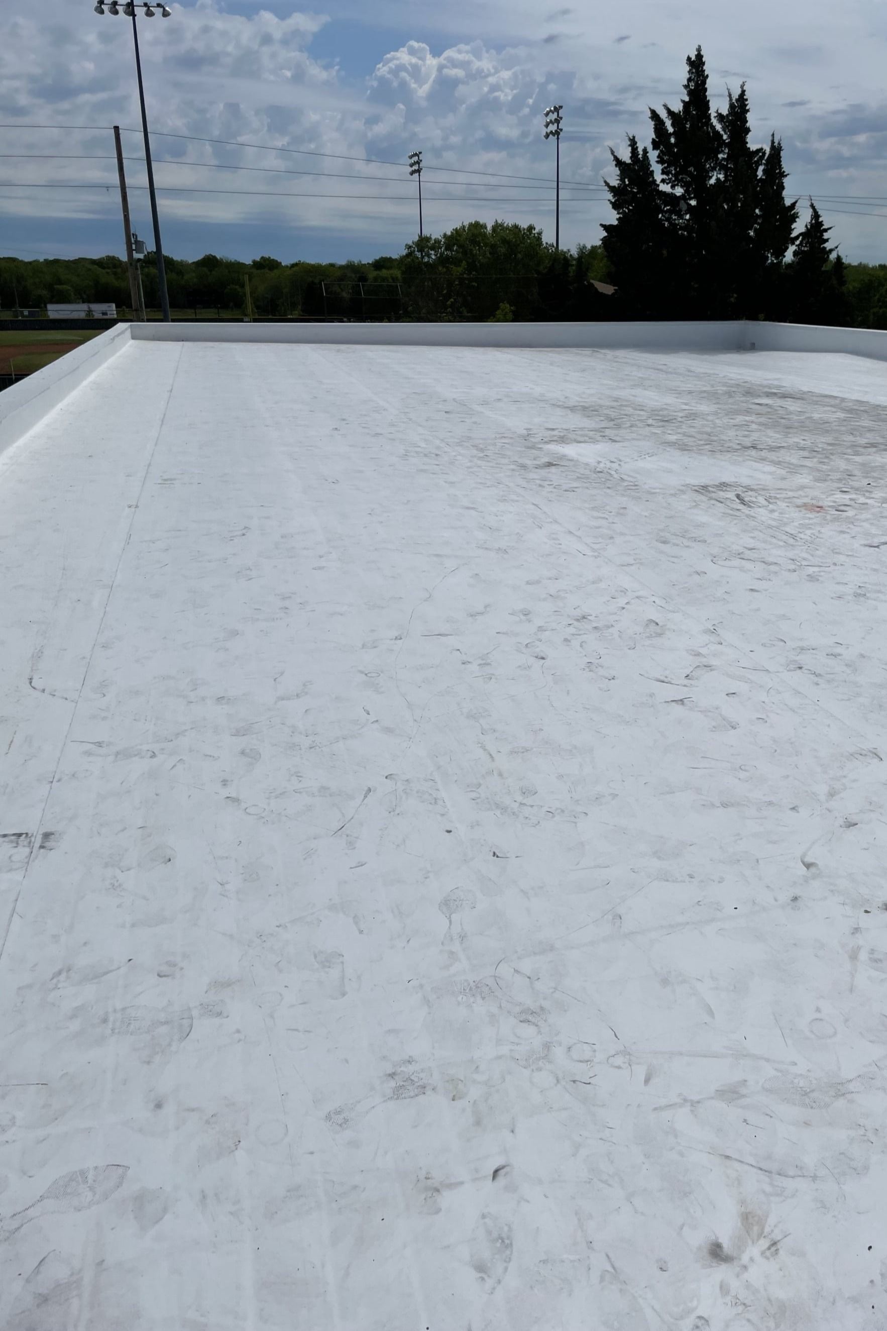 A white roof with trees in the background and a blue sky in the background.