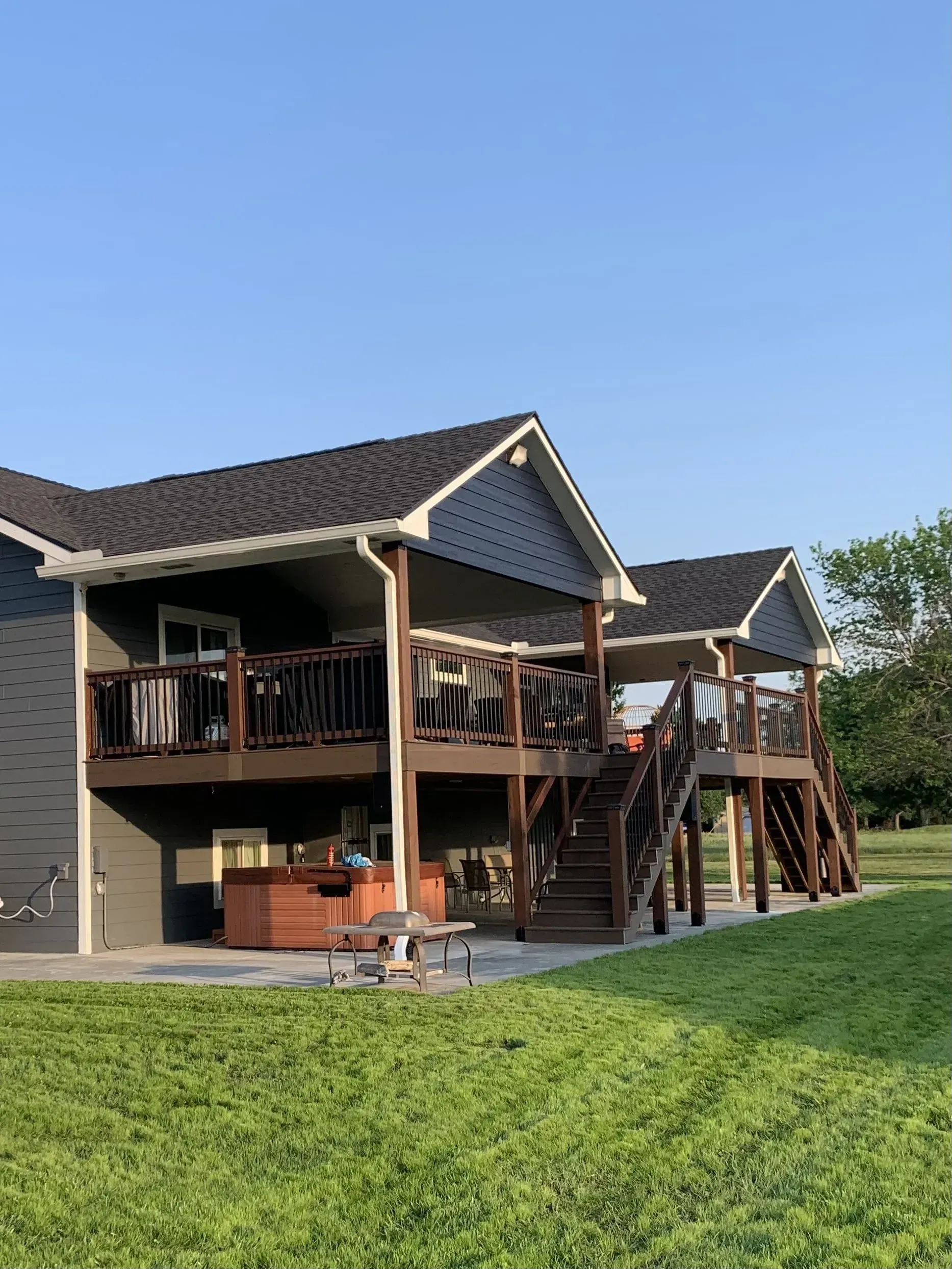 A large house with a large deck and a hot tub in the backyard.