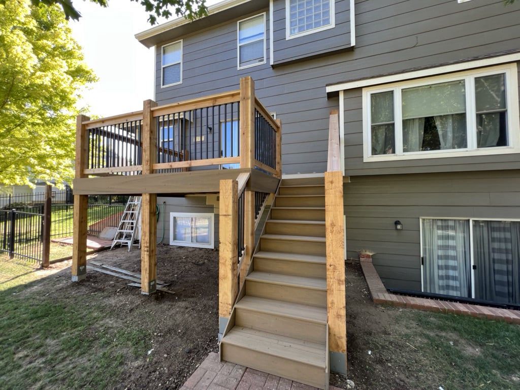 A deck with stairs leading up to it is in the backyard of a house.