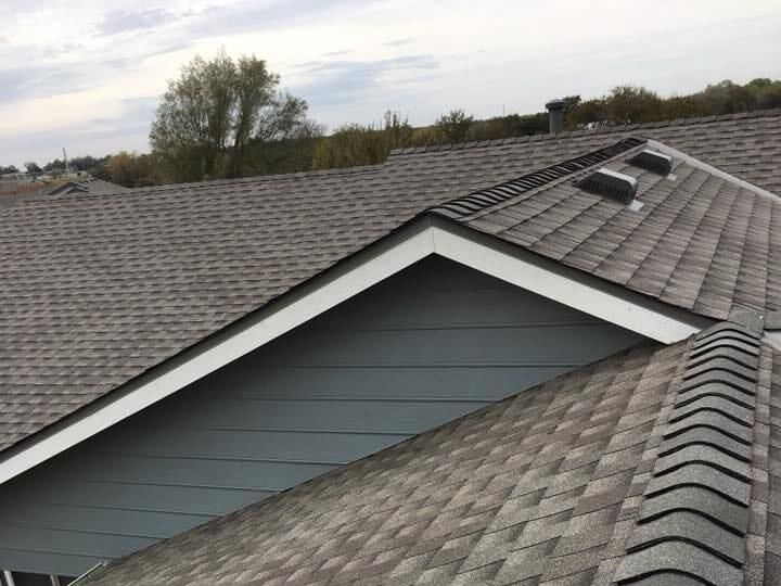 The roof of a house with a gray shingle roof and a white trim.