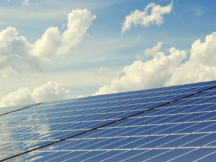 A row of solar panels against a blue sky with clouds