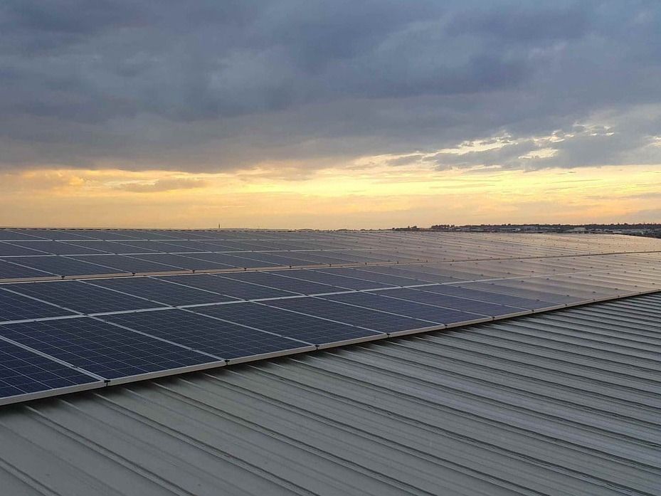 There are many solar panels on the roof of a building.