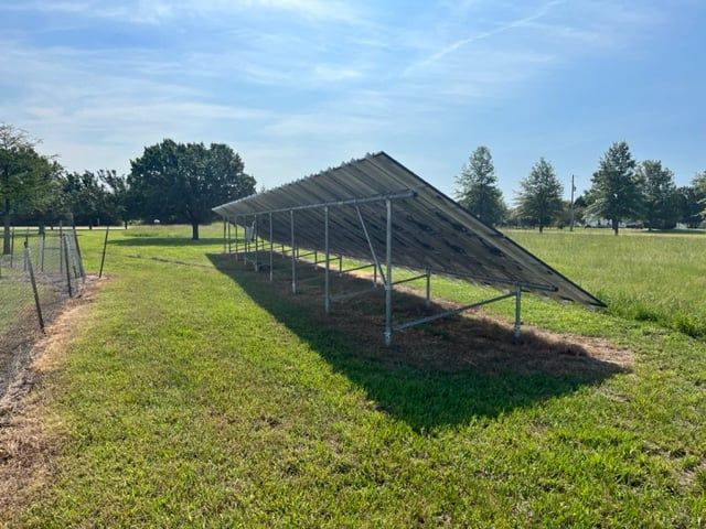 A row of solar panels are sitting in a grassy field.