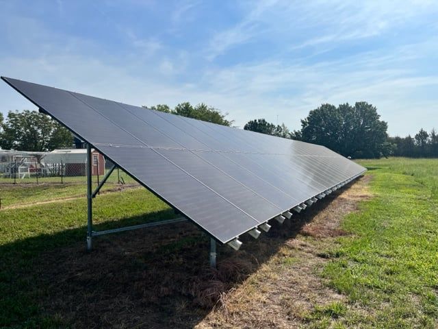 A row of solar panels are sitting in a grassy field.