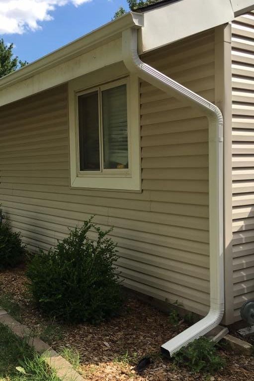 A house with a gutter on the side of it and a window.