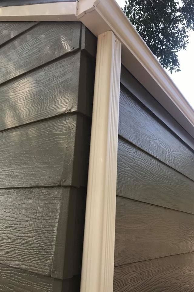 A close up of a gutter on the side of a house.