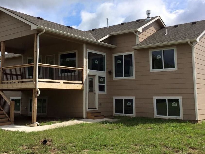 The back of a house with a deck and a lot of windows