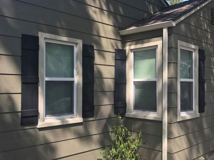 A house with two windows and black shutters on the side.