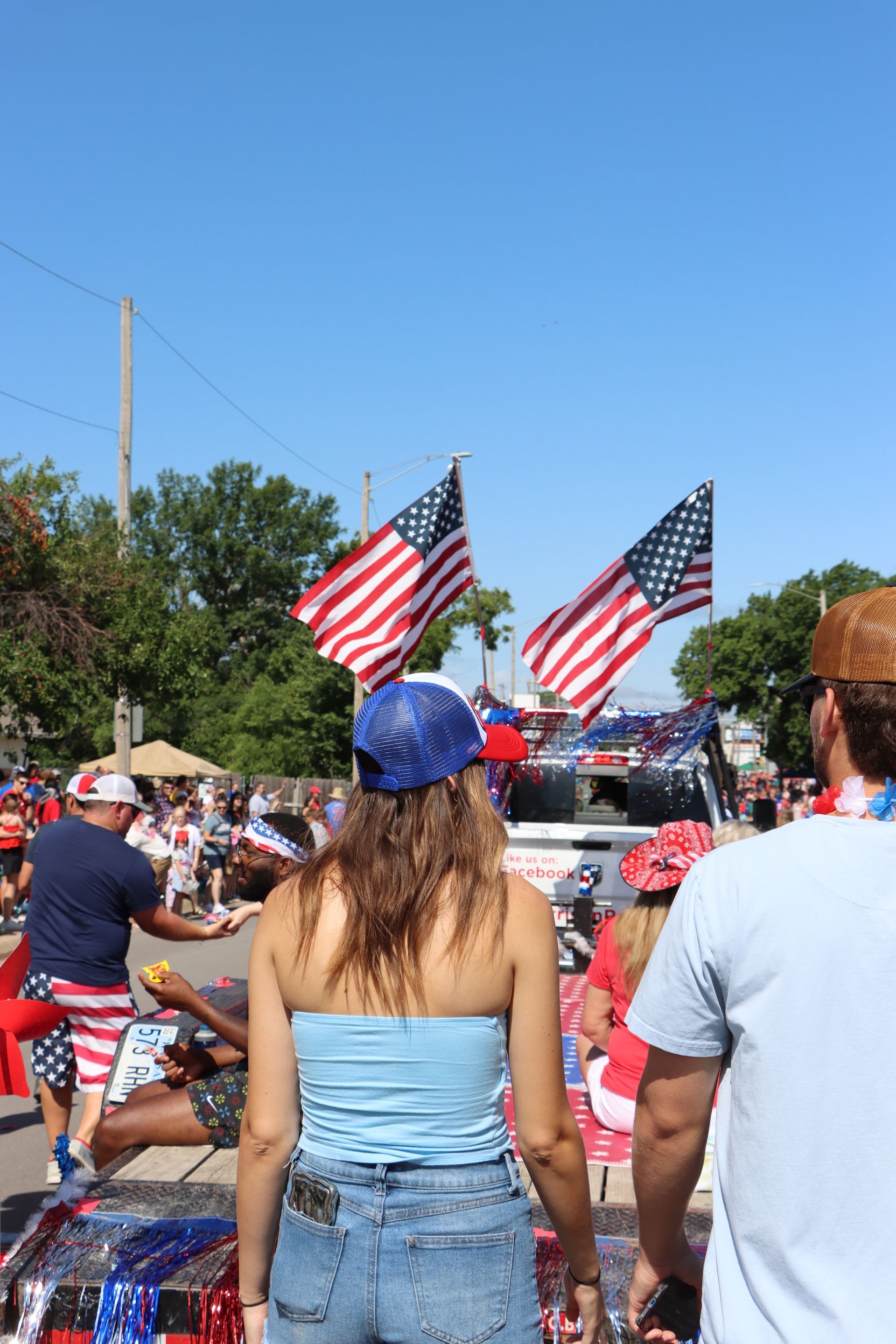 A woman is standing in front of a crowd of people watching a parade.