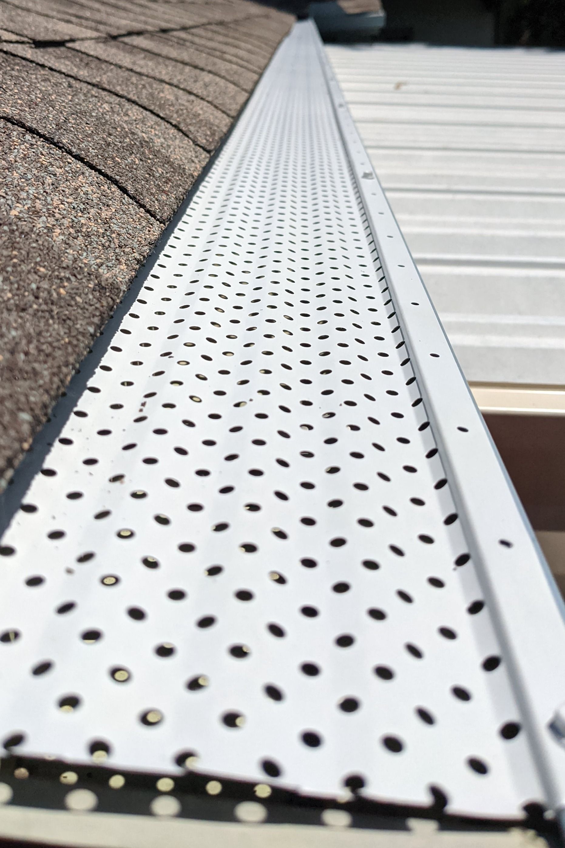 A white gutter with black dots on it is sitting on top of a roof.