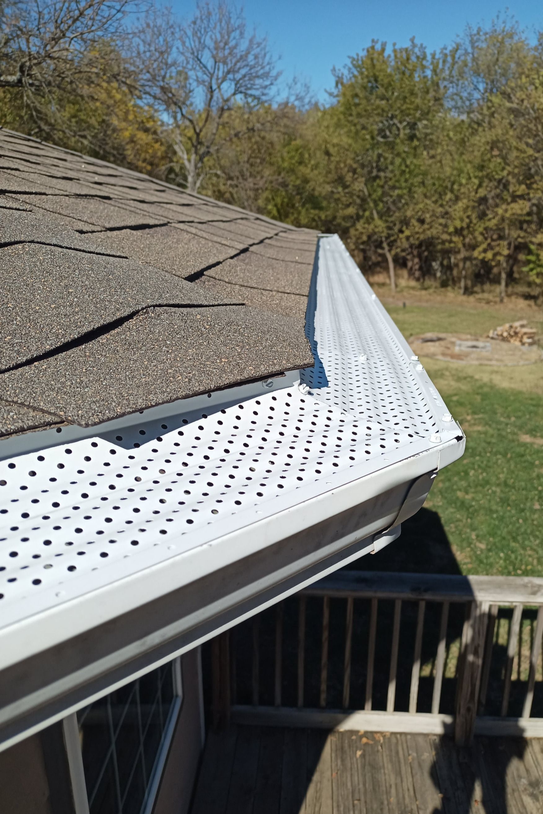 A gutter on the side of a house next to a deck.