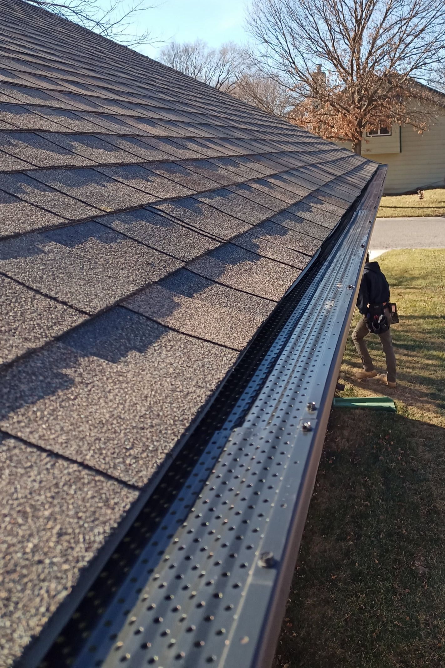 A man is standing next to a gutter on the side of a roof.
