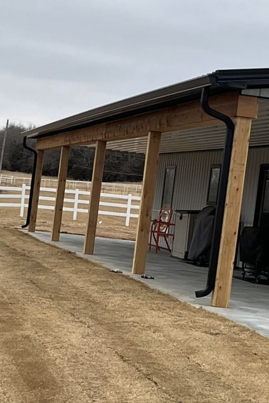 A wooden covered porch with a white fence in the background.