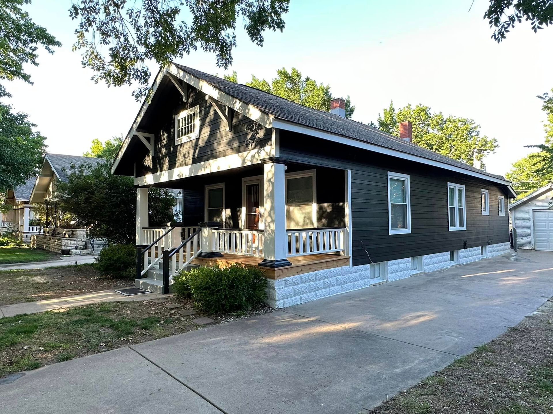 A black house with white trim and a porch