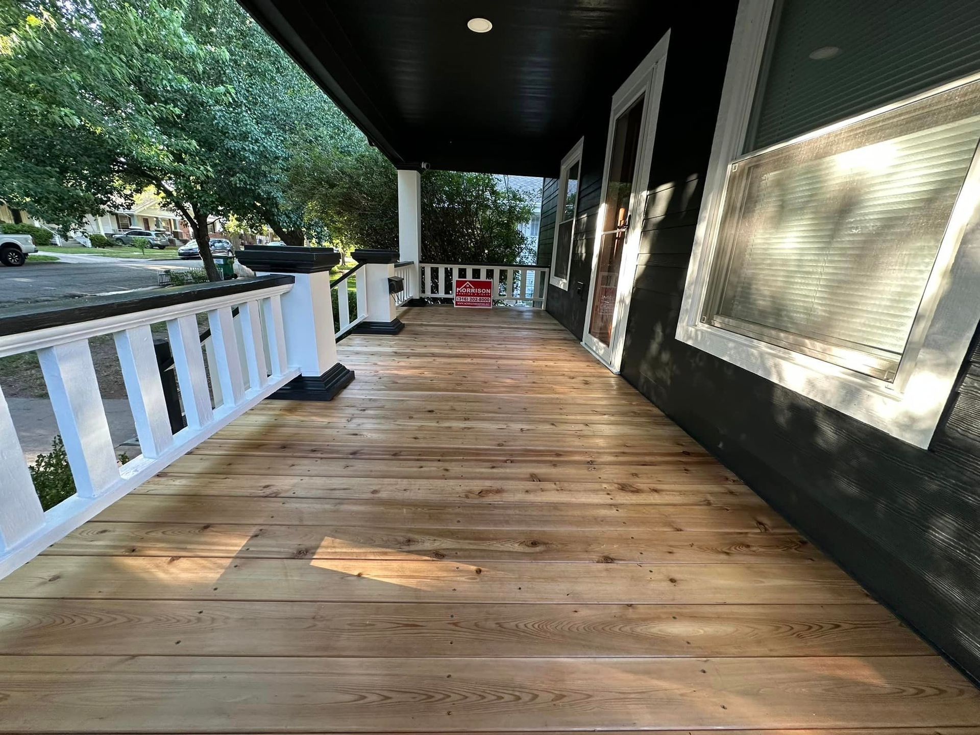 A porch with a wooden floor and a white railing.