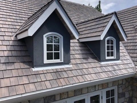 There are two windows on the roof of a house.
