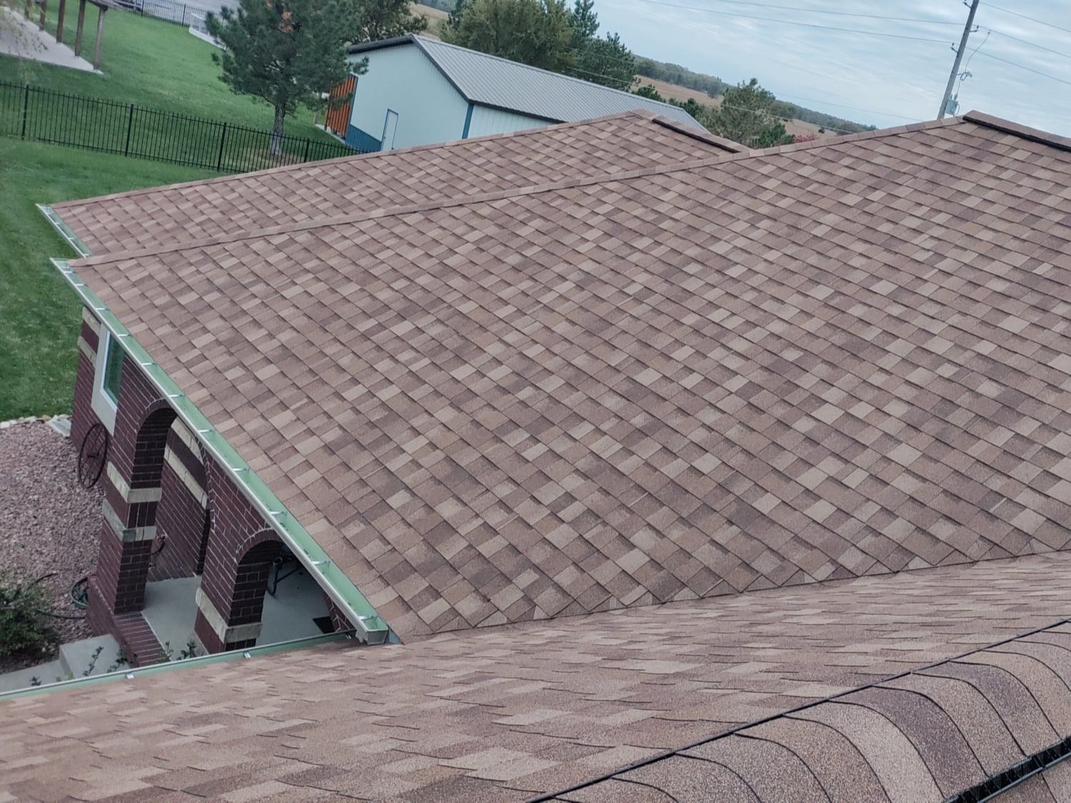 The roof of a house with a brown shingle roof.