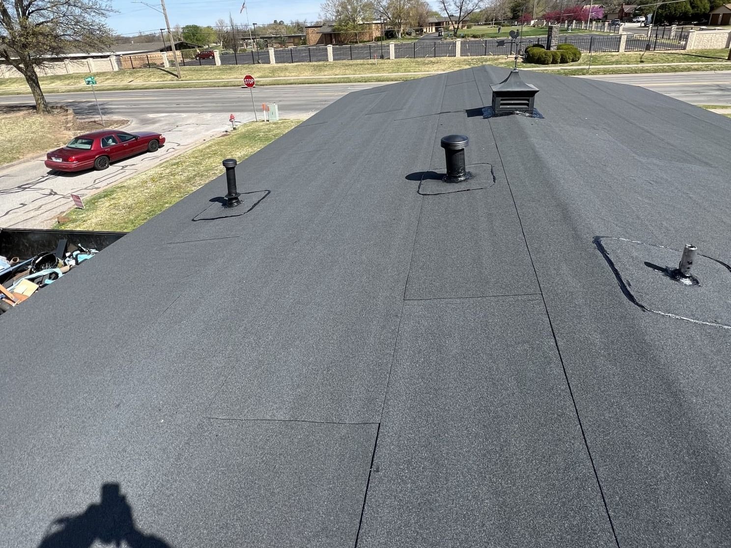 A black roof with a red car parked in the background.