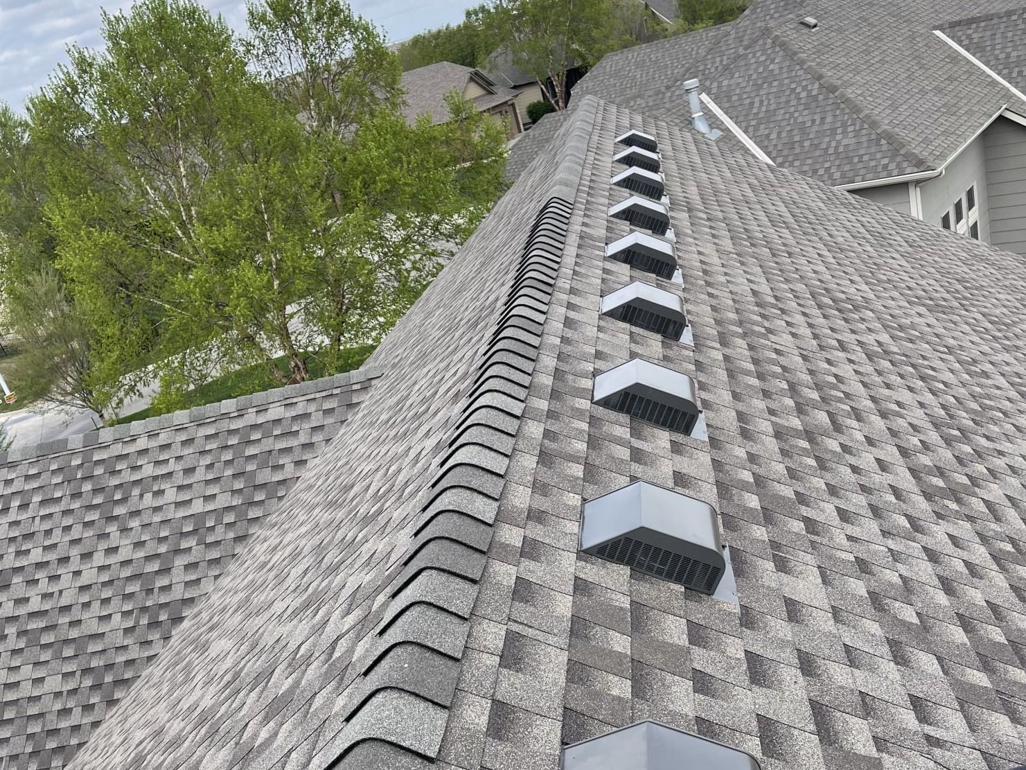 A roof with a row of vents on it and trees in the background.