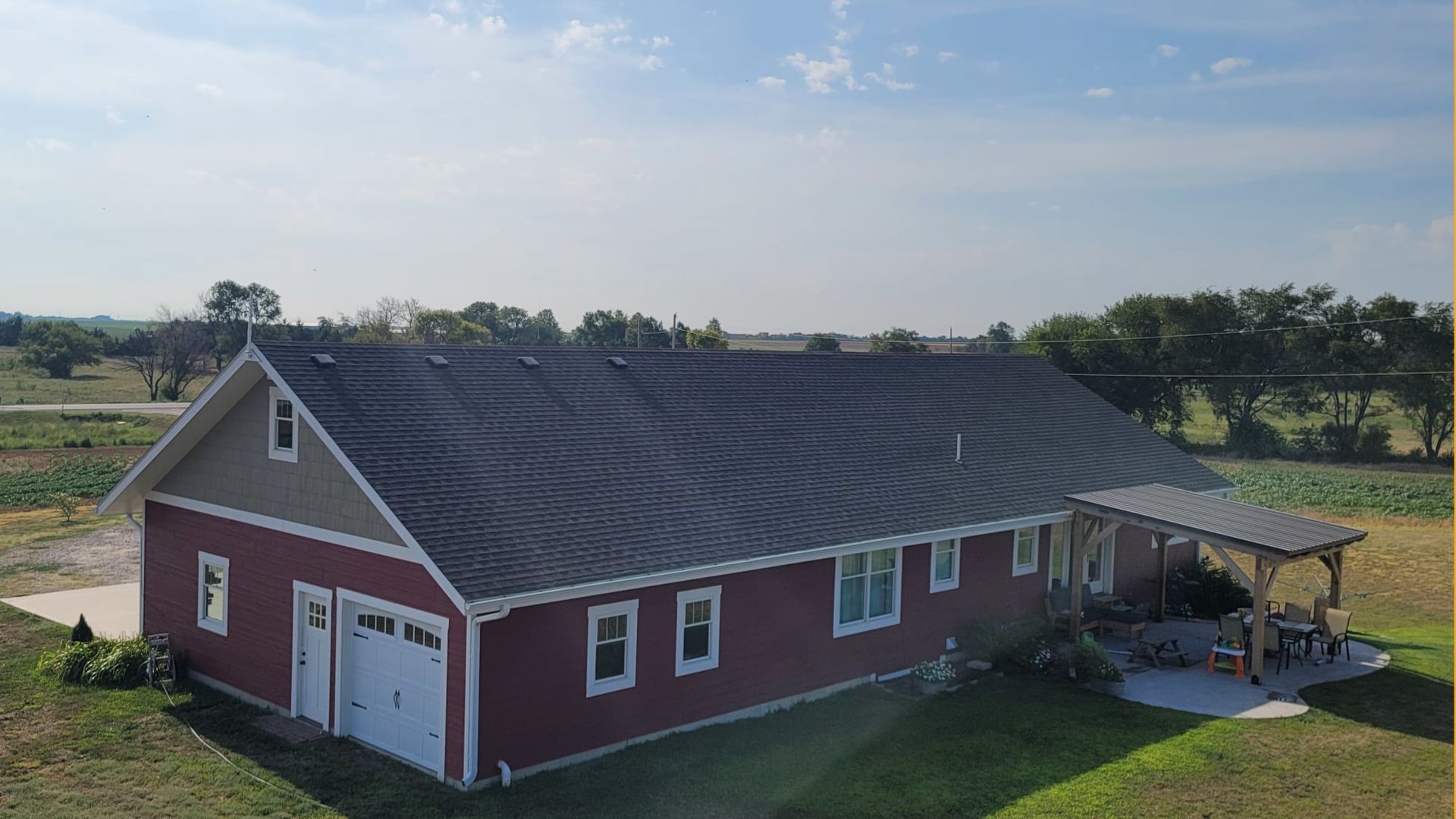 An aerial view of a large red house with a garage and a porch.