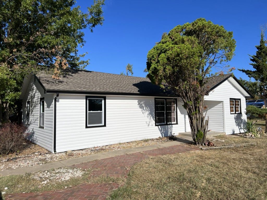 A small white house with a tree in front of it.