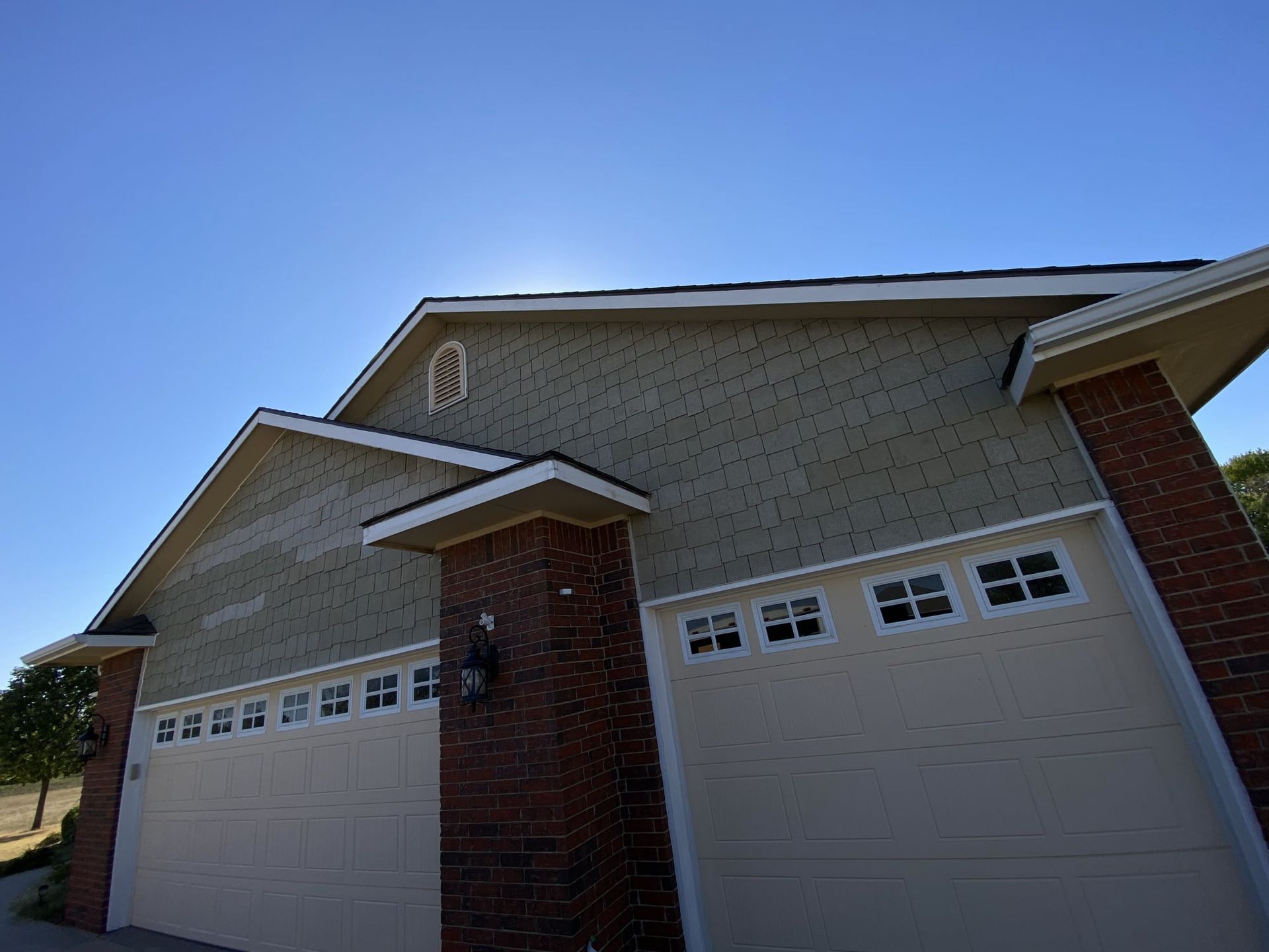 A house with two garage doors and a blue sky in the background