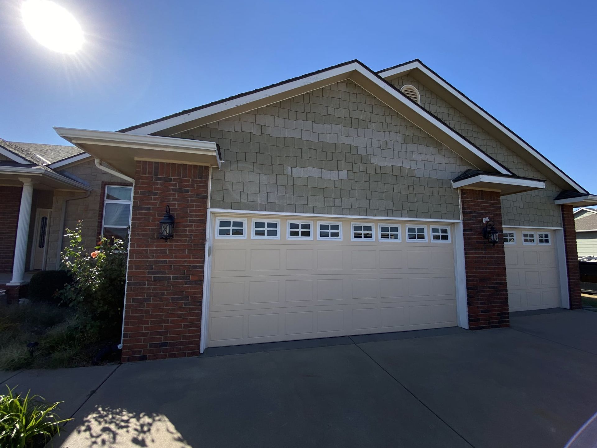 A house with two garage doors and a blue sky in the background