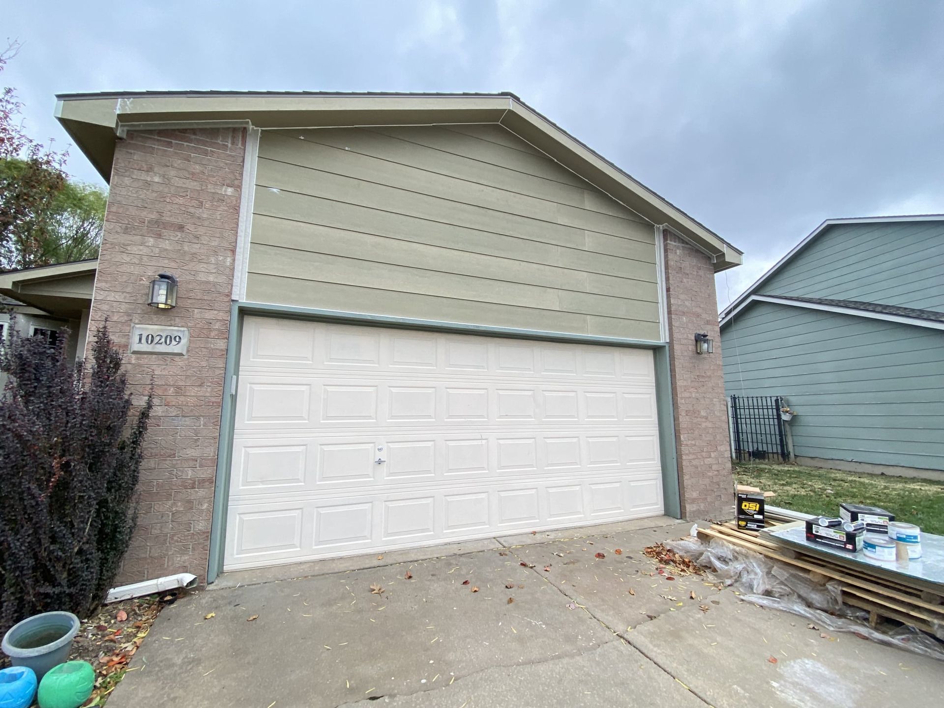 A white garage door is sitting in front of a brick house.