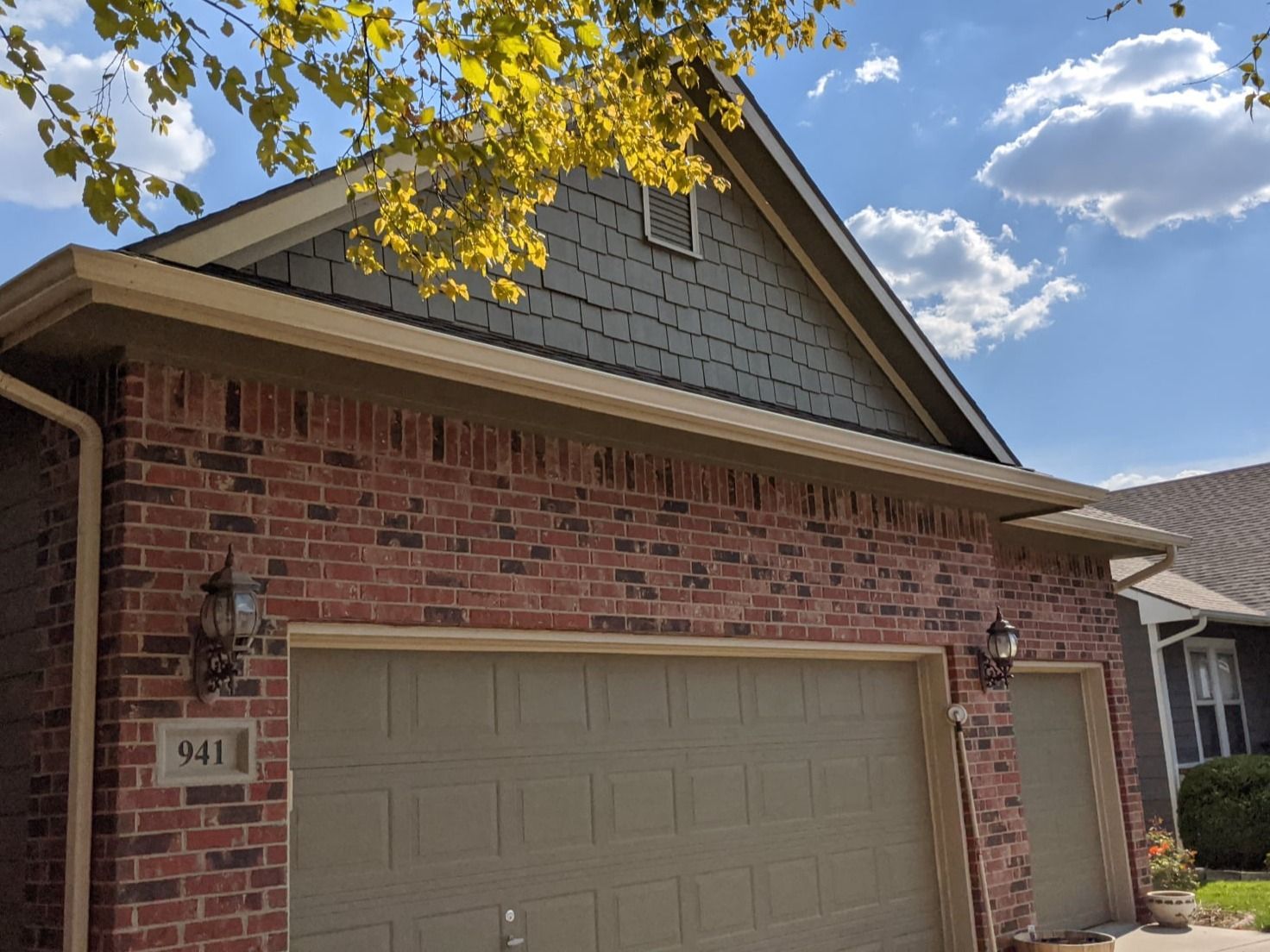 A brick house with two garage doors and a roof