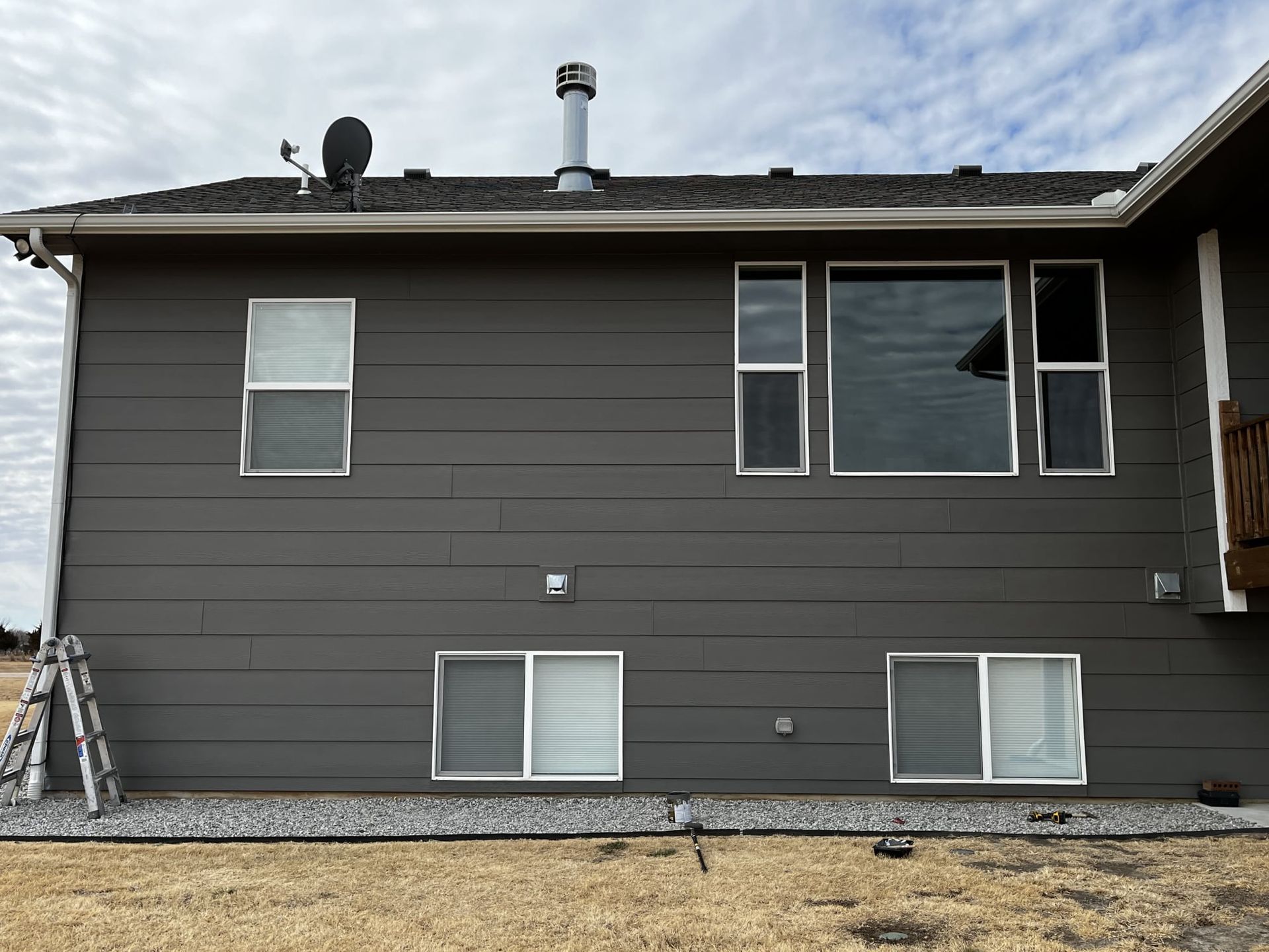 The back of a house with a lot of windows and a chimney on the roof.