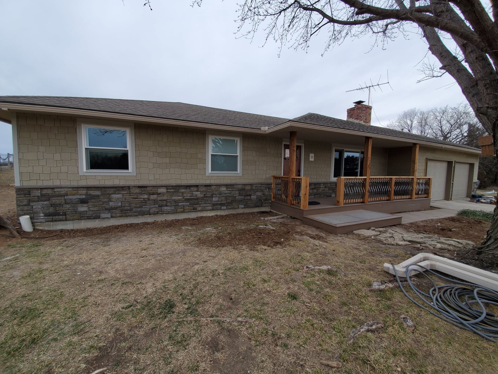 A house with a porch and a tree in front of it.