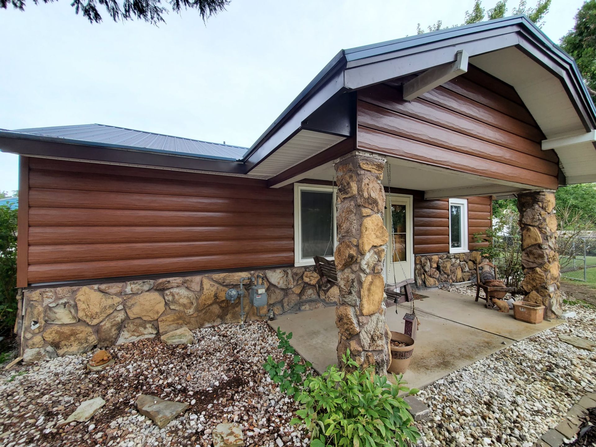 A log cabin with a stone wall and a porch