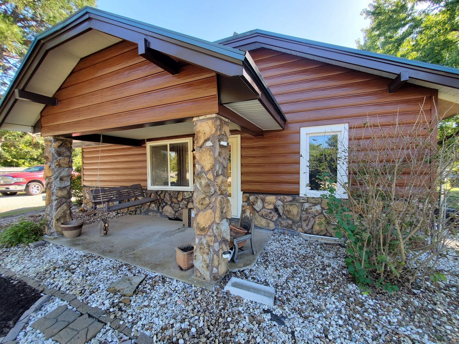 A log cabin with a porch and a stone wall