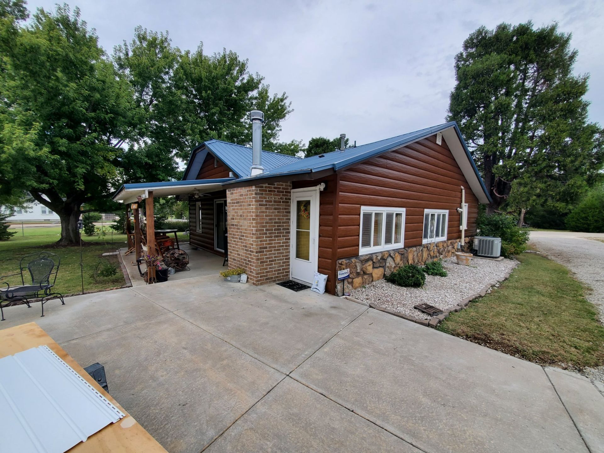 A log cabin with a blue roof and a driveway
