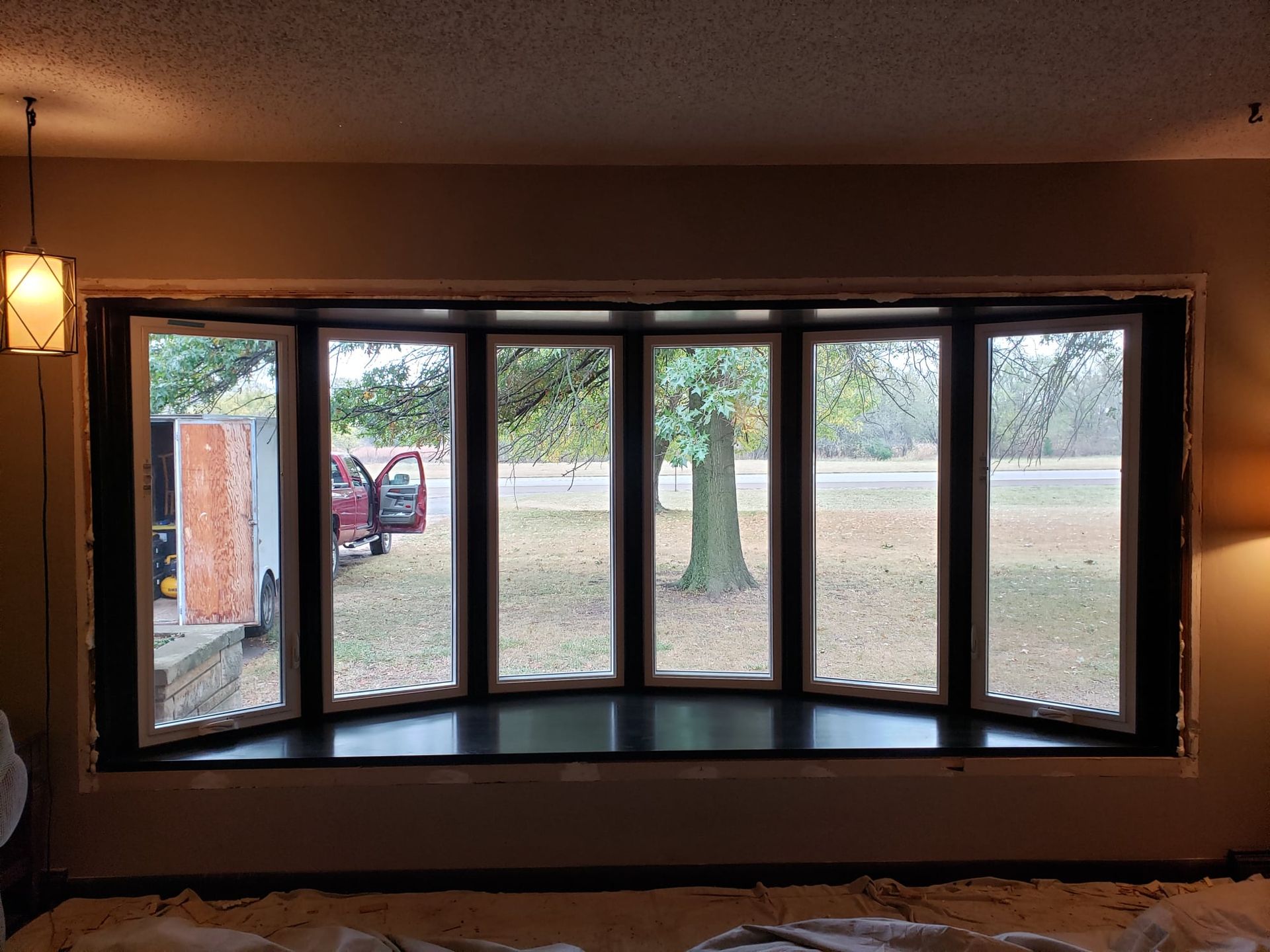 A living room with a large bay window looking out to a yard.