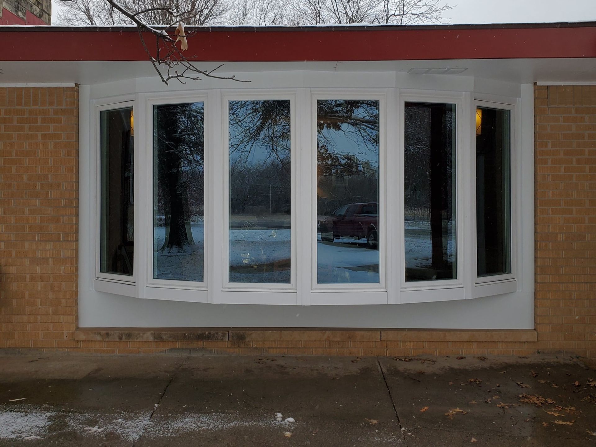 A large white bay window on the side of a brick building.