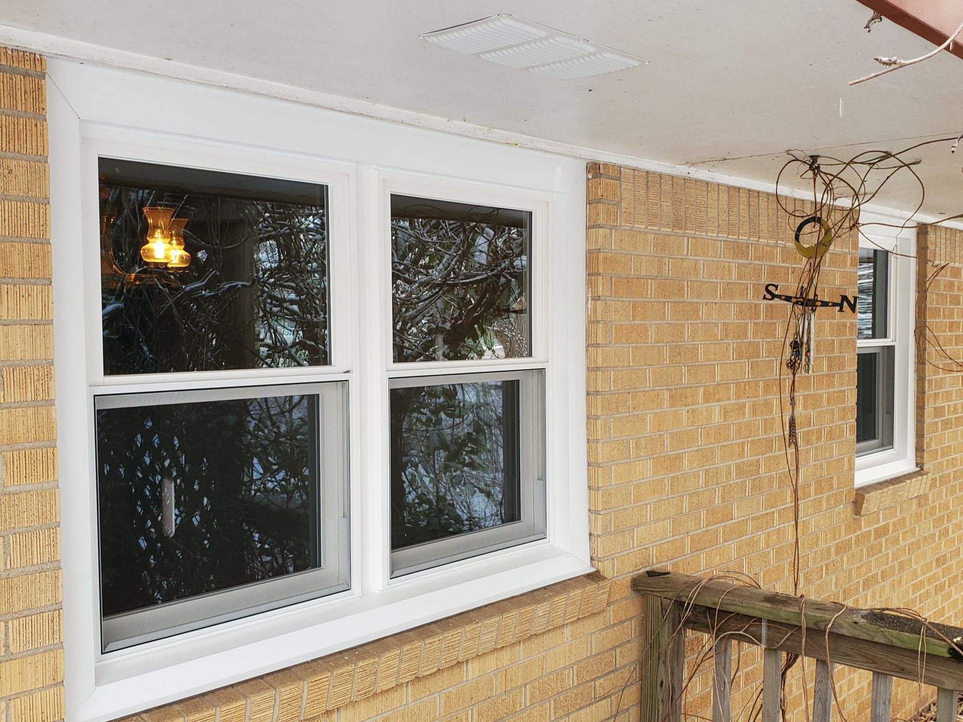 There are two windows on the side of a brick building.