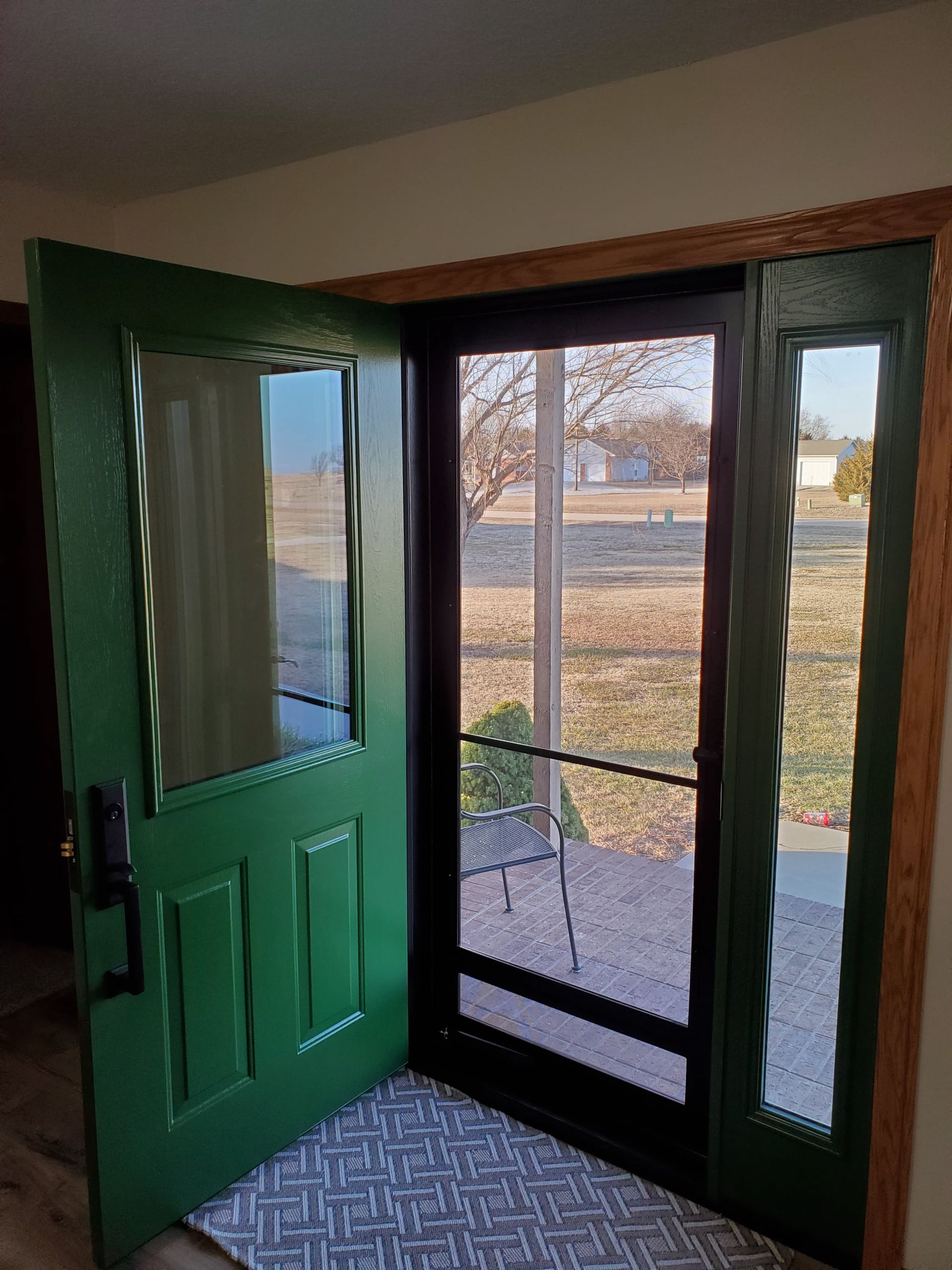 A green door is open to a screened in porch.
