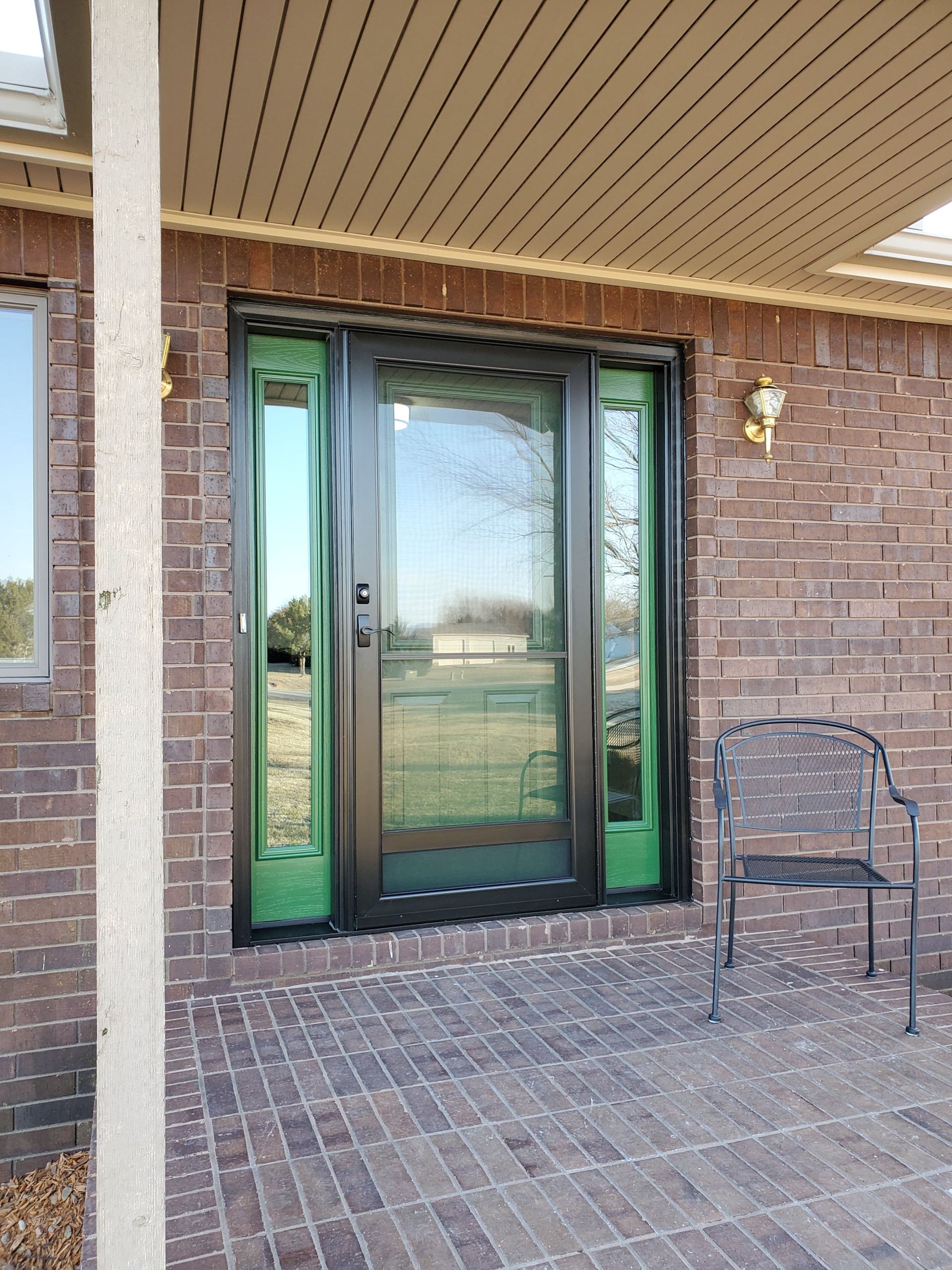 A brick house with a green door and a chair