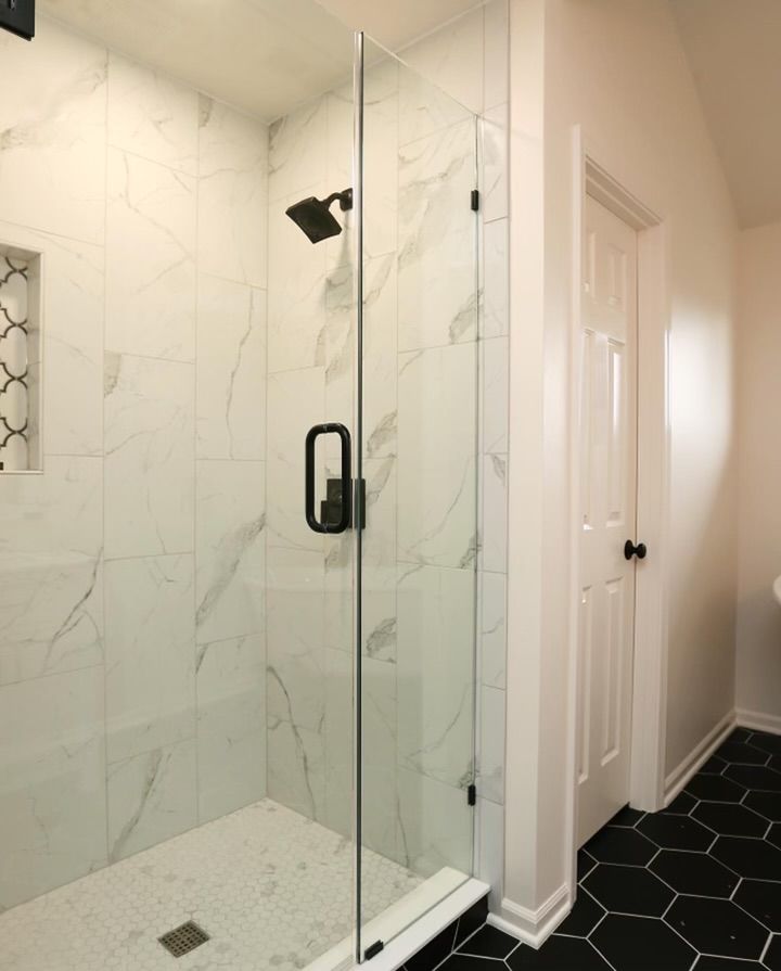 A bathroom with a walk in shower with a glass door