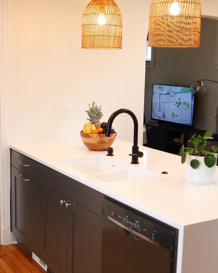 A kitchen with a sink, dishwasher, and a bowl of fruit on the counter.