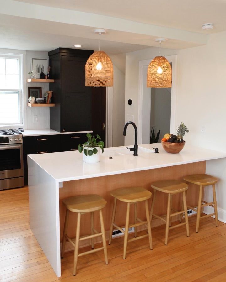 A kitchen with a large island, stools and a sink.