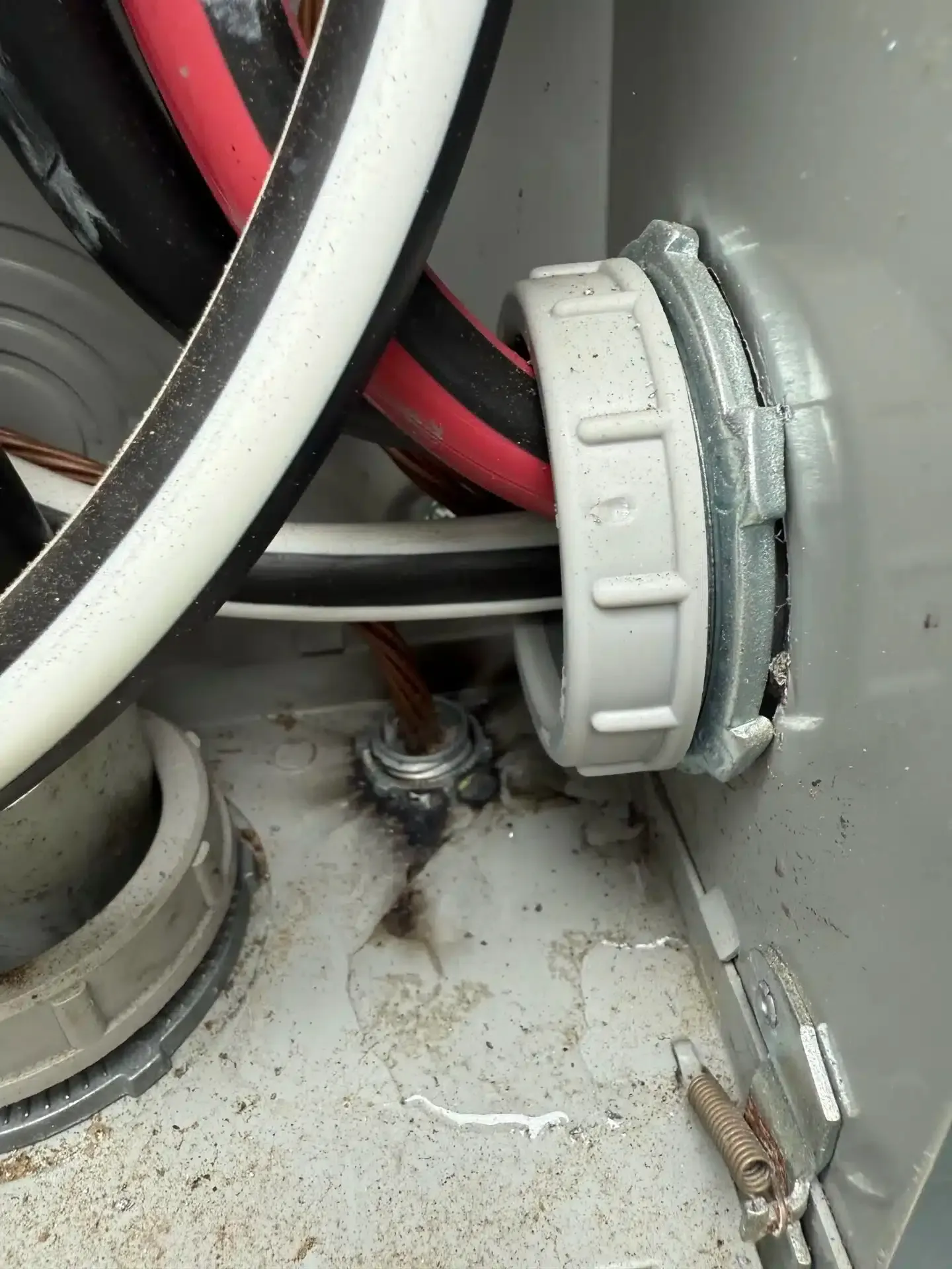 Electrical wires entering a metal box through a connector. Ground wire is bolted to the box.