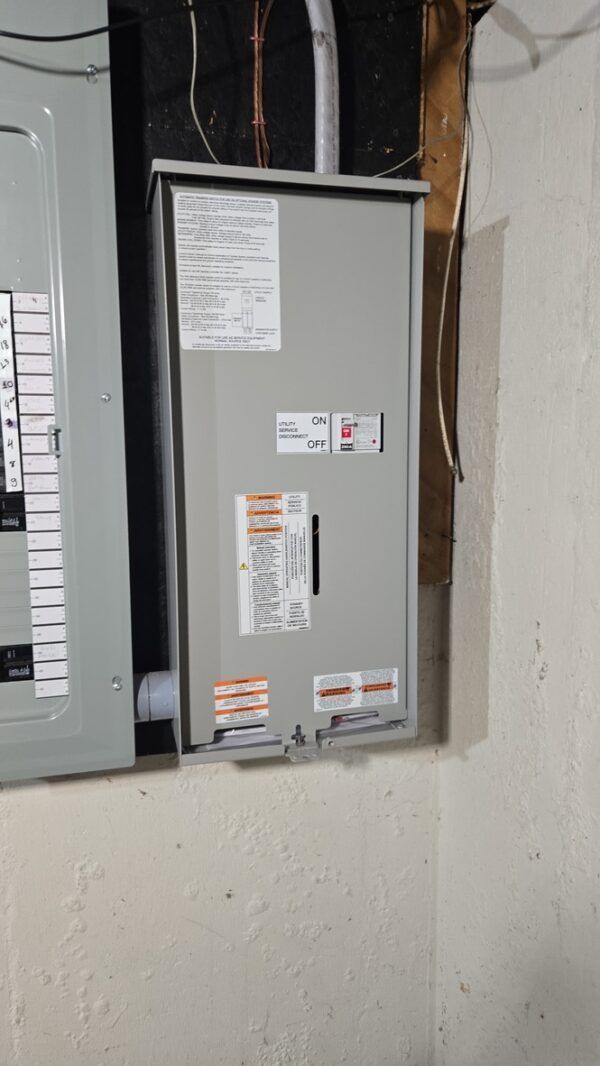 Electrical panel with labels, gray metal box mounted on a white wall in a corner.