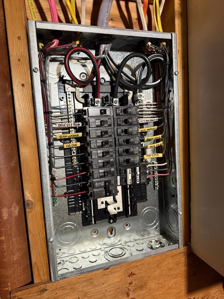 Electrical panel with multiple circuit breakers and wiring inside a metal box.