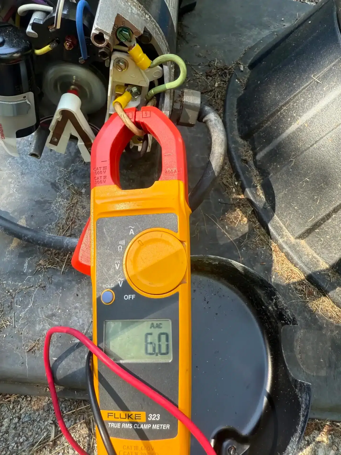 A multimeter clamped around a wire reads 6.0 Amps, next to a motor.