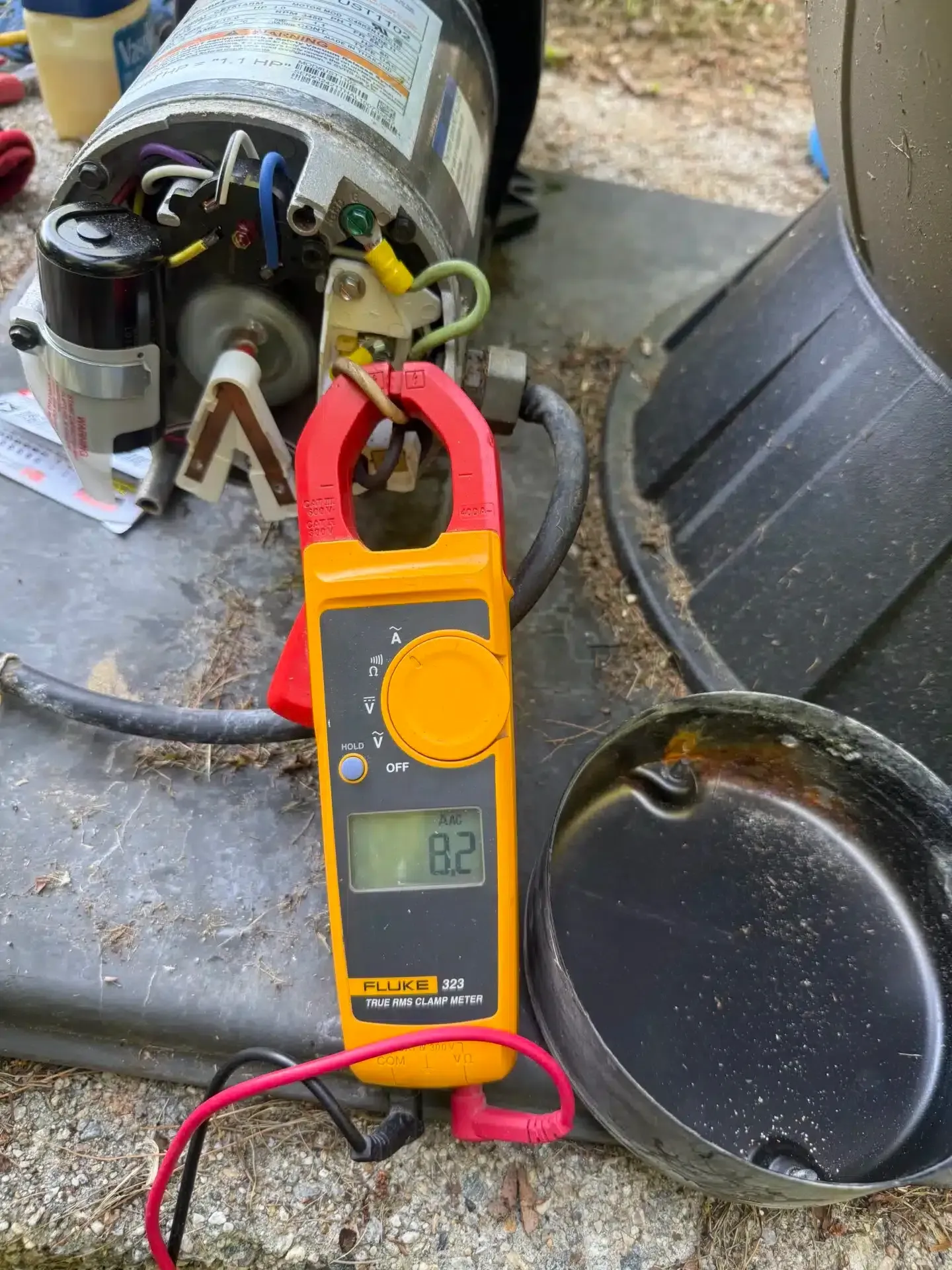 A clamp meter displays 8.2 amps while measuring a pool pump motor's current.