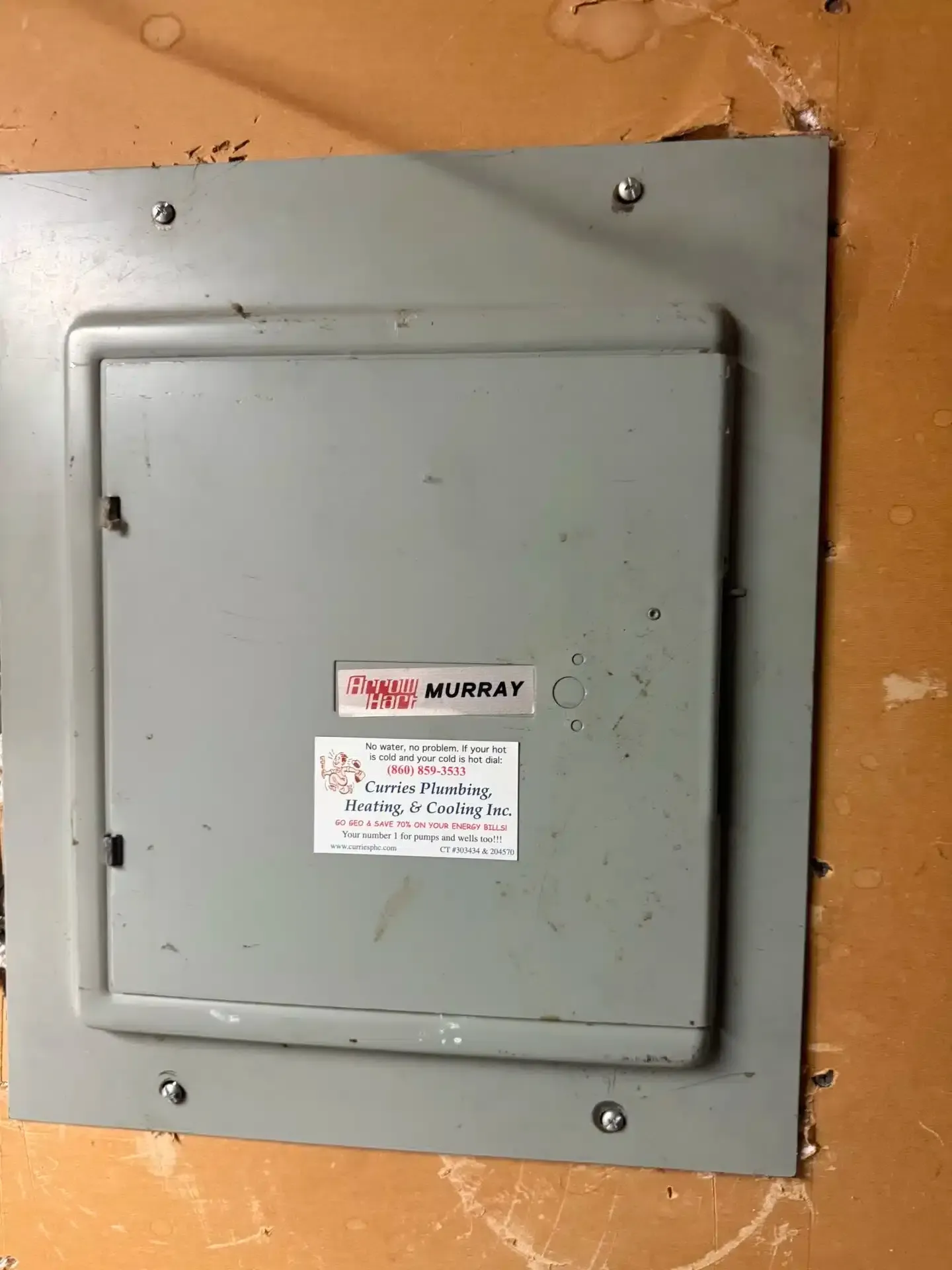 Gray electrical panel with Murray label mounted on a tan wall.