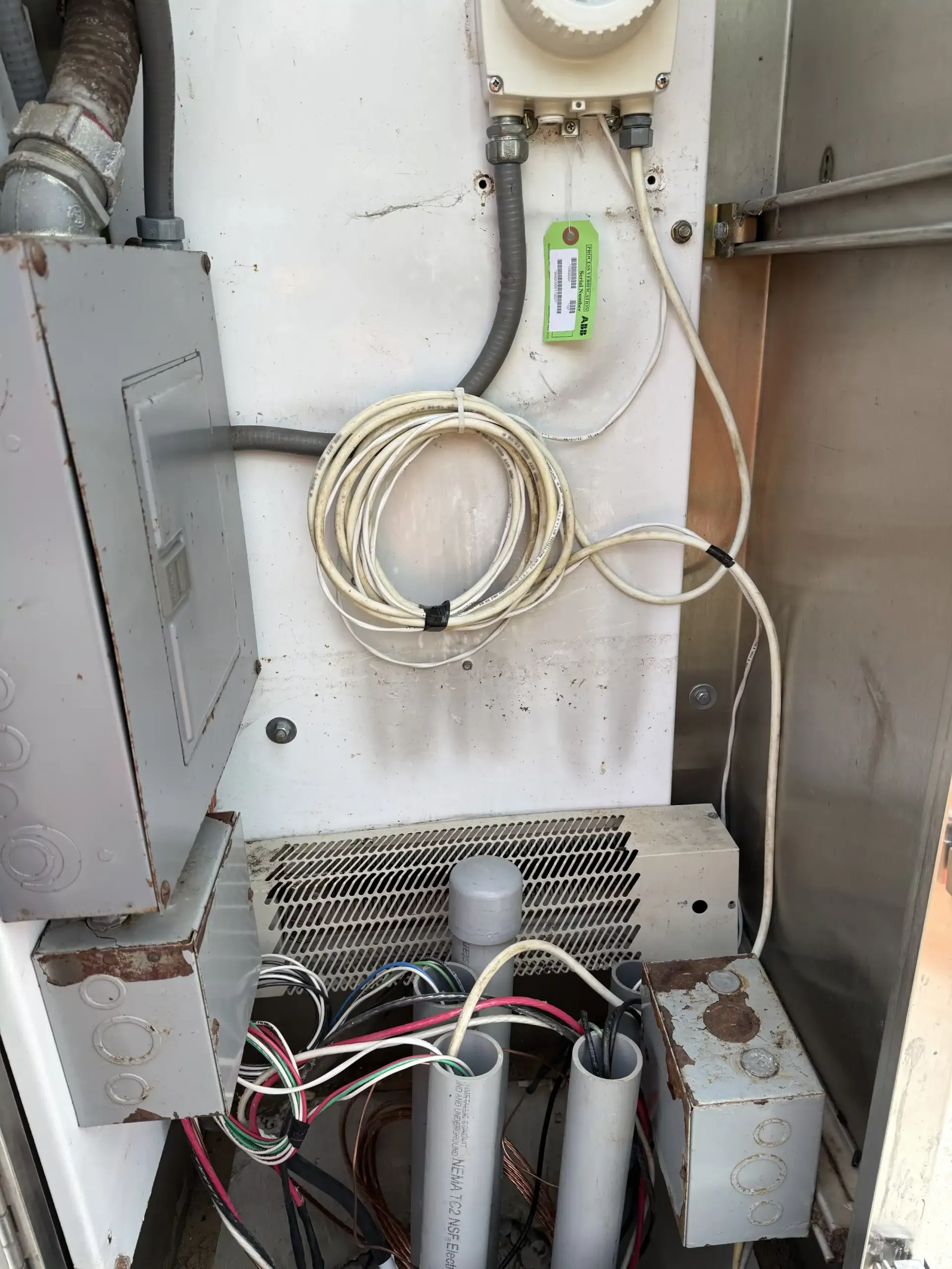 Interior of electrical panel showing wires, conduit, and components in a metal cabinet.